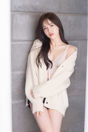 カジュアルな服装で灰色のコンクリートの壁に向かってポーズをとる若い女性をポートレート...。