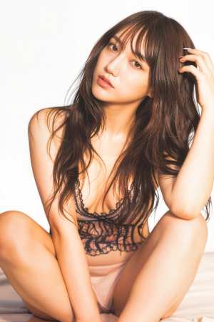 ウェーブのかかった茶色の長い髪をした若い女性が、薄手の黒いレースのブラジャーとそれに...。