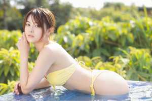 緑豊かな緑に囲まれたプールでポーズをとる、黄色いビキニを着た若い女性を横から撮った写...。