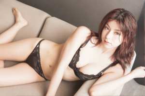 黒いレースのランジェリーを着て、ベージュのソファにリラックスしたポーズで横たわってい...。