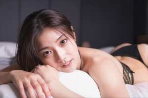 ベッドに横たわり、リラックスした表情でカメラを見つめる若い女性をクローズアップカメラ...。