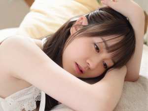 ベージュのソファにうつ伏せになり、頭を手に乗せている若い女性の接写。