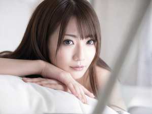 長く真っ直ぐな茶色の髪と印象的な青い目を持ち、カメラを直接見つめながら顎を手に乗せた...。