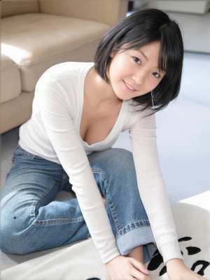 白い長袖シャツとブルー ジーンズを着て、モダンなリビング ルームの敷物の上にしゃがむ...。