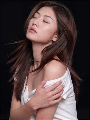 黒い背景のスタジオ設定で、白いオフショルダーのトップスを着た、長い茶色の髪をなびかせ...。