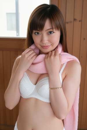 白いブラジャーとピンクのスカーフを身に着け、カジュアルな服装でポーズをとる若い女性を...。