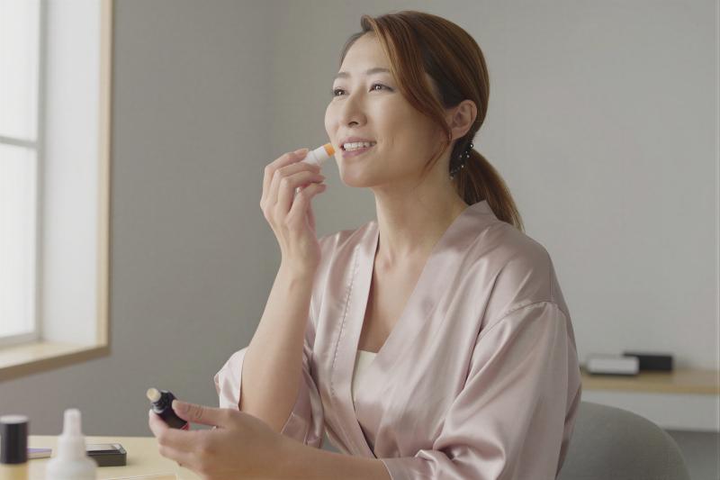 寝室でリップケアする女性