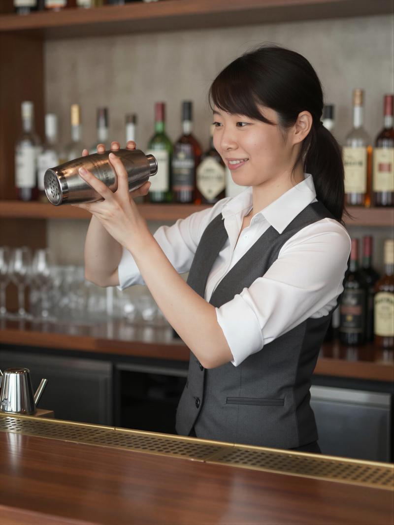 バーテンダーの女性がカクテルをシェイク