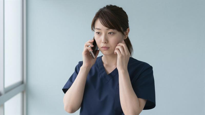 廊下で電話をする看護師
