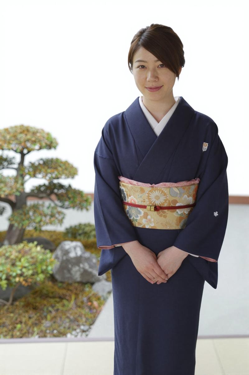 旅館の庭園で客を迎える女性