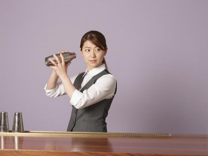 バーカウンターでカクテルを作る女性