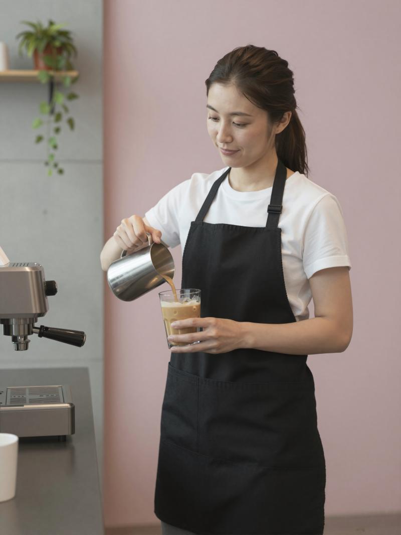 モダンカフェでアイスラテを作る女性