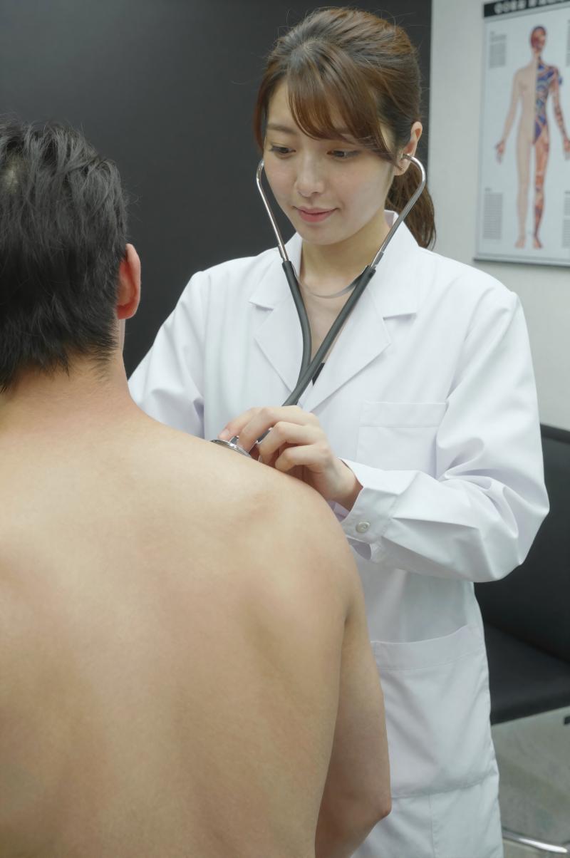 診察室で背中を診察する医師