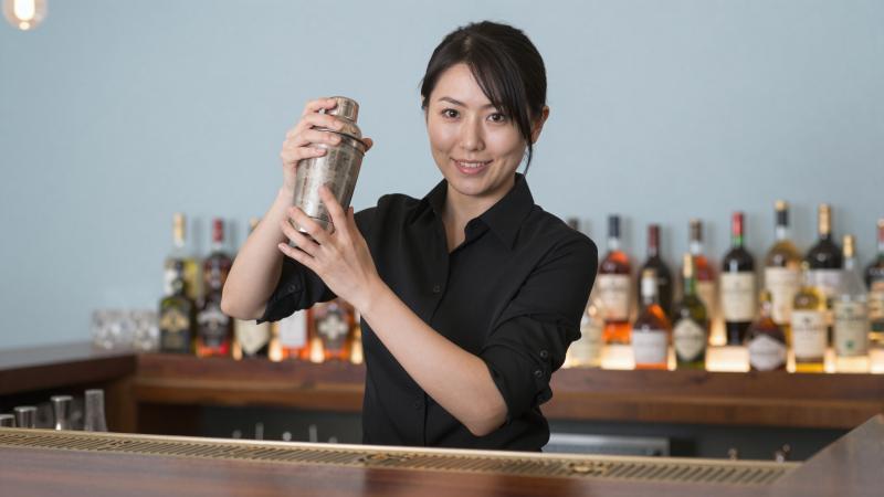 バーでカクテルをシェイクするバーテンダー