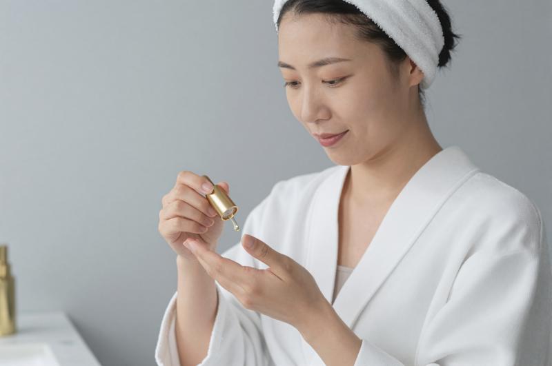 手のひらに美容オイルを垂らす女性