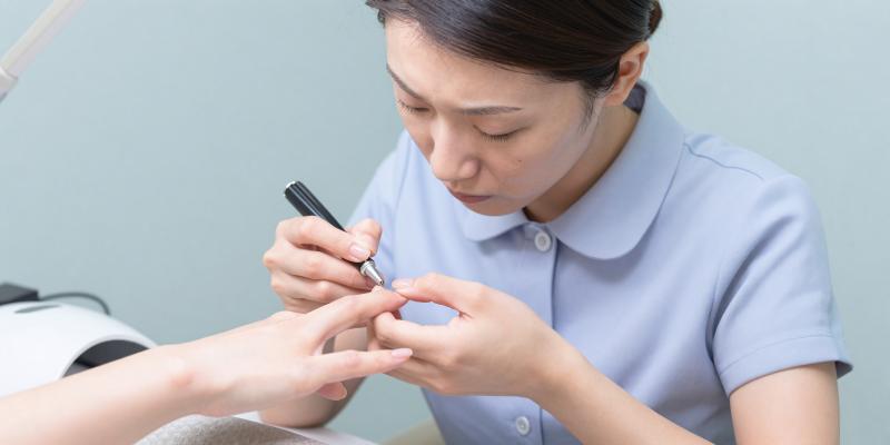 ジェルランプでトップコートを塗るネイリスト