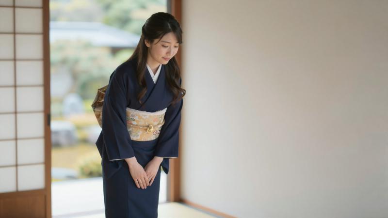 旅館で客を迎える着物姿の女性