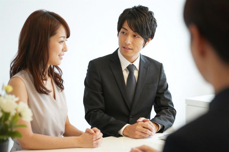 ホテル受付で客の要望を聞く男性