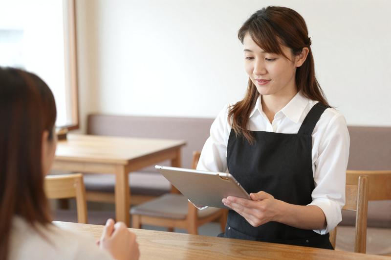 カフェでタブレットで注文を取る女性