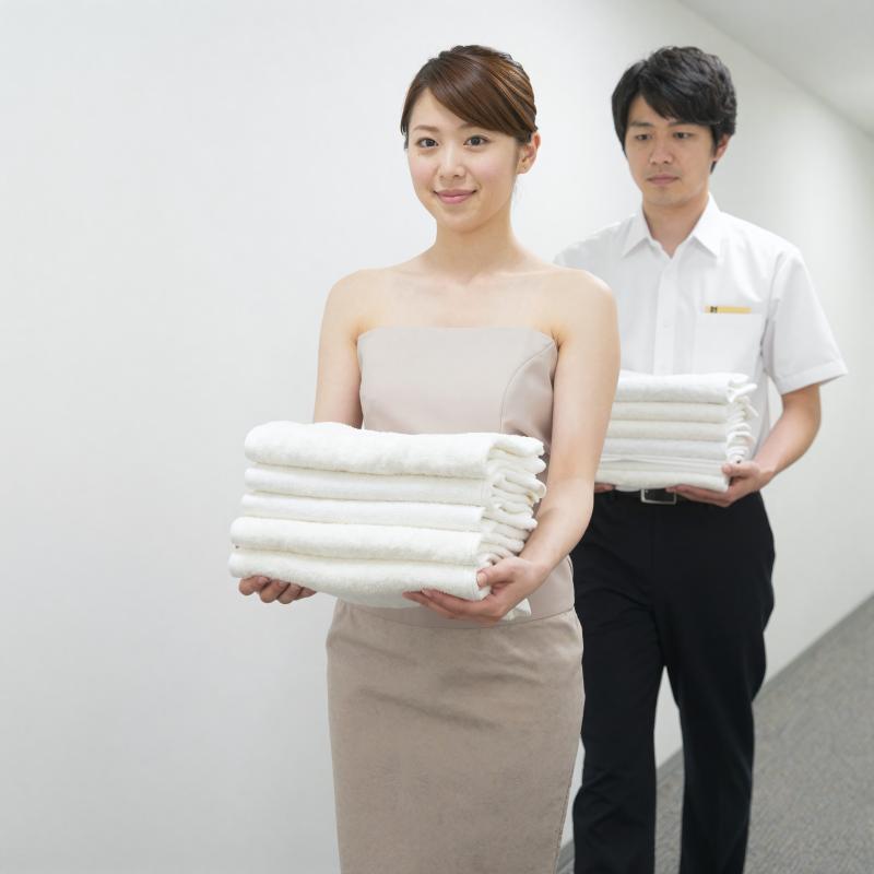 ホテル廊下でタオルを運ぶ男性スタッフ