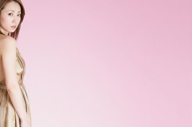 ピンク背景の金髪女性が振り返るポートレート