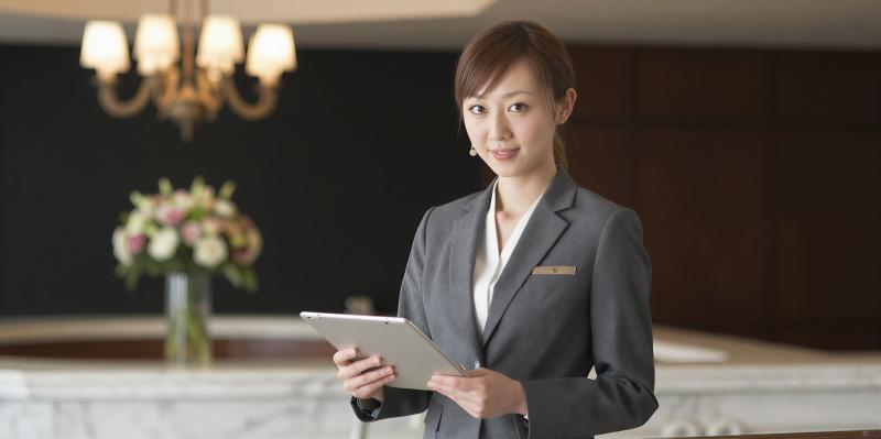 ホテルフロントでタブレットを操作する女性スタッフのポートレート
