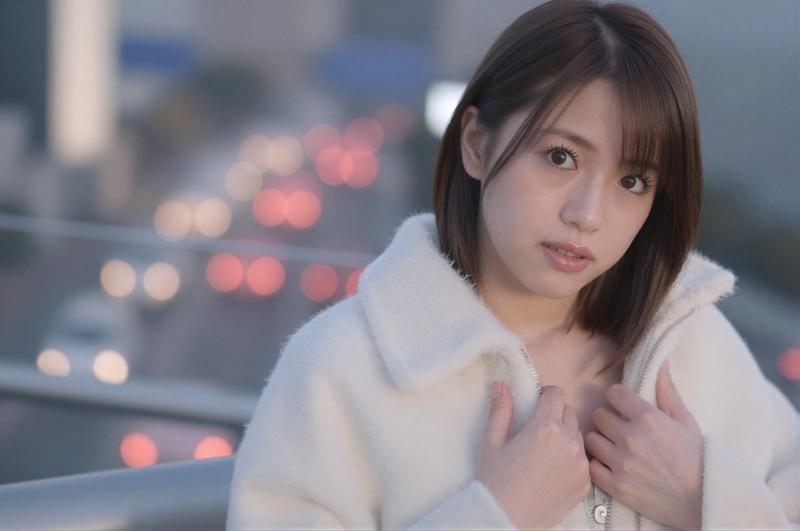 都会の夜景を背景にした白いコートの女性ポートレート