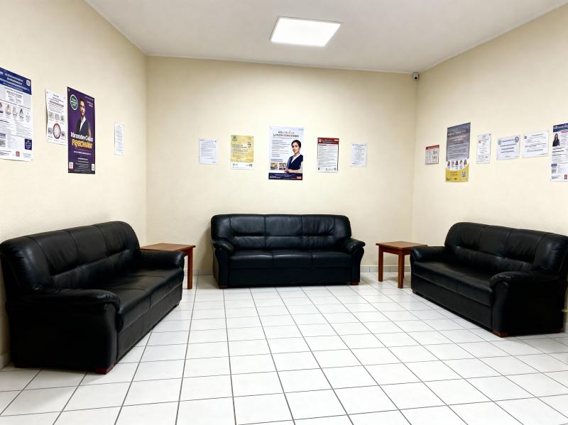 3 つの黒い革張りのソファと壁にポスターが置かれた待合室の写実的なレンダリング。