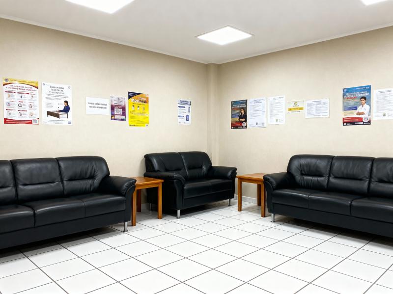 部屋の中央に 3 つの黒い革張りのソファと 2 つの小さな木製テーブルがある待合室の...。