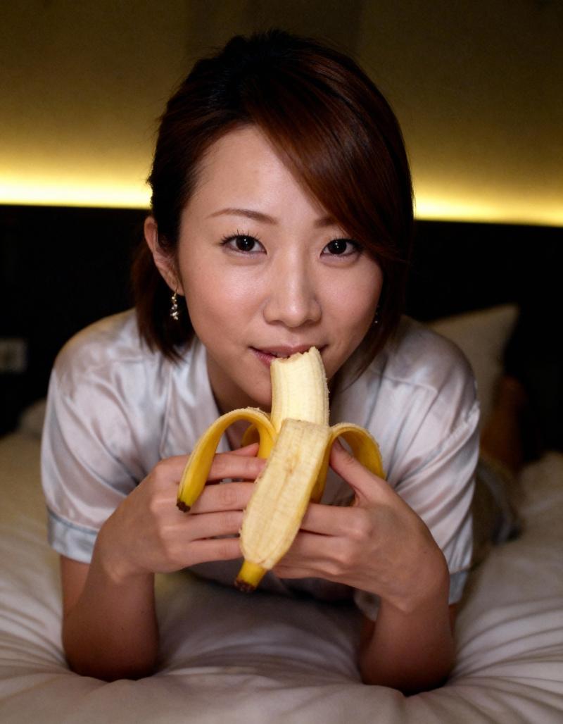 顔の前にバナナを持ってベッドに横たわる若い女性を、クローズアップ カメラ アングルか...。