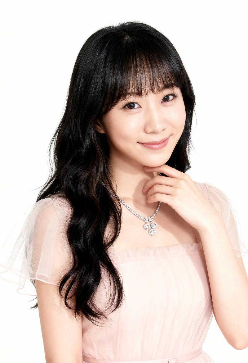 ウェーブのかかった長い黒髪と前髪を持ち、薄手の袖と繊細なネックレスが付いた淡いピンク...。