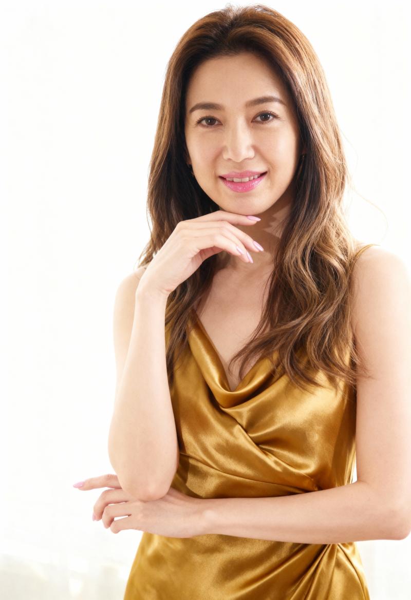 金色のシルクのドレスを着た、ウェーブのかかった茶色の長い髪を持つ若い女性のプロのポー...。