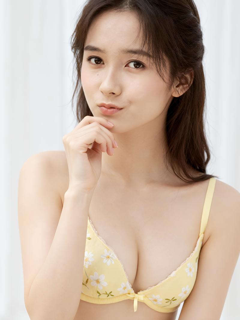 黄色の花柄のブラジャーを着て思慮深くポーズをとる若い女性をポートレートアングルから撮...。