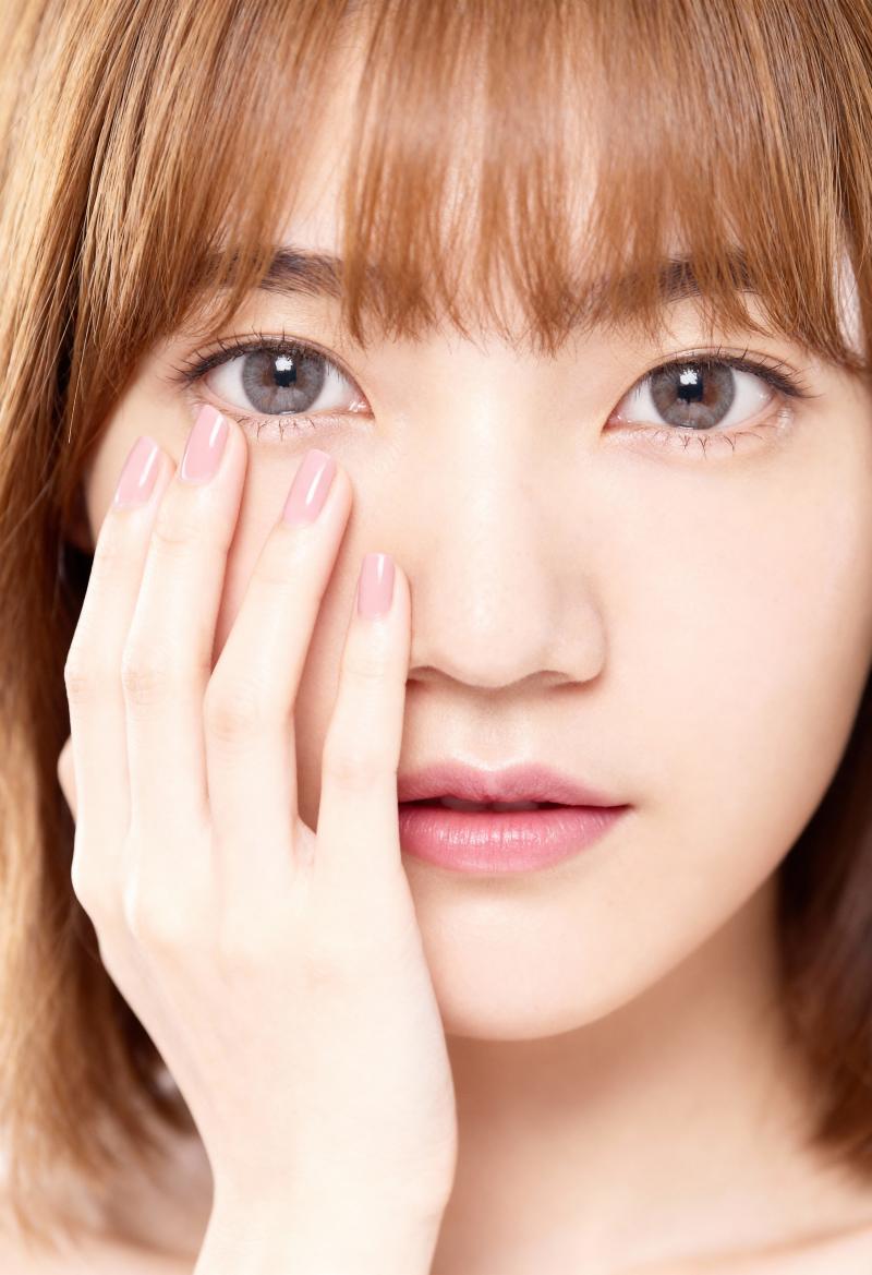 右手で顔に触れながら、思慮深い表情をしたアジア系の若い女性の接写。