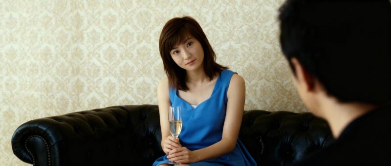 シャンパングラスを手に黒い革張りのソファに座り、注意深く座っている男性を見つめている...。