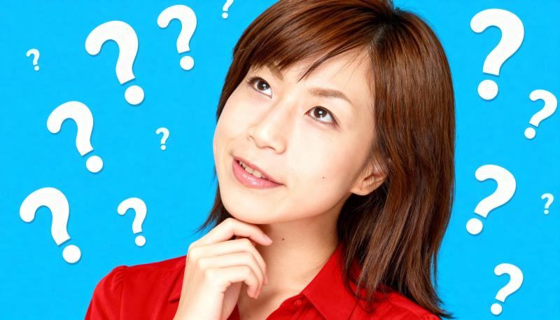 明るい青色の背景に疑問符で囲まれた、思慮深い表情を持つ若いアジア人女性のポートレート。