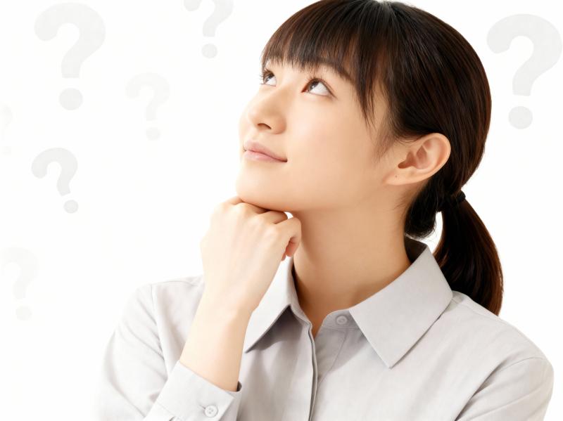 水色の襟付きシャツを着た、思慮深い表情をしたアジア系の若い女性が、あごを手に乗せてフ...。