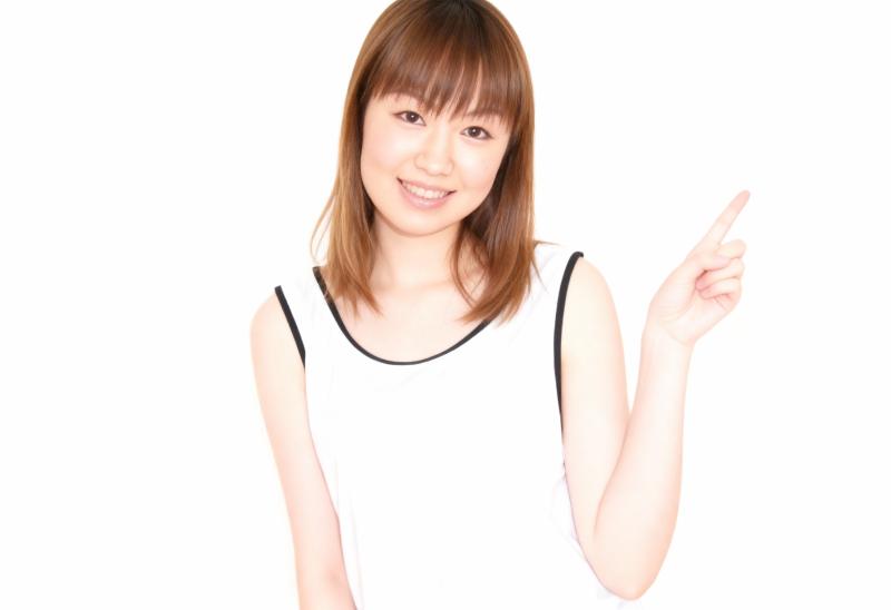 人差し指で上を指し、明るい表情をしたアジア系の若い女性。