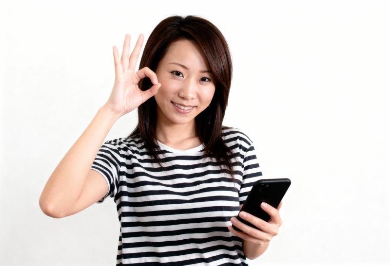 画像の中央に立っている若いアジア人女性は、黒と白の縞模様の T シャツを着て、右手に...。