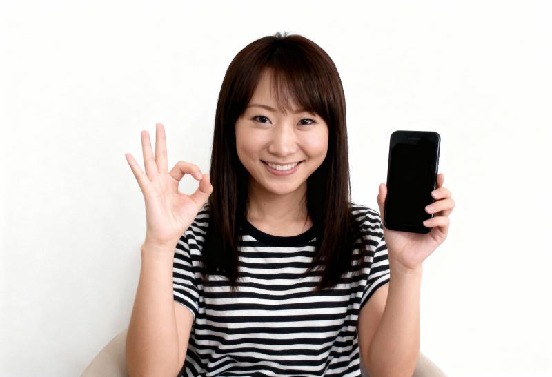 画像の中央に座っている若いアジア人女性は、右手に黒いスマートフォンを持ち、左手で「O...。