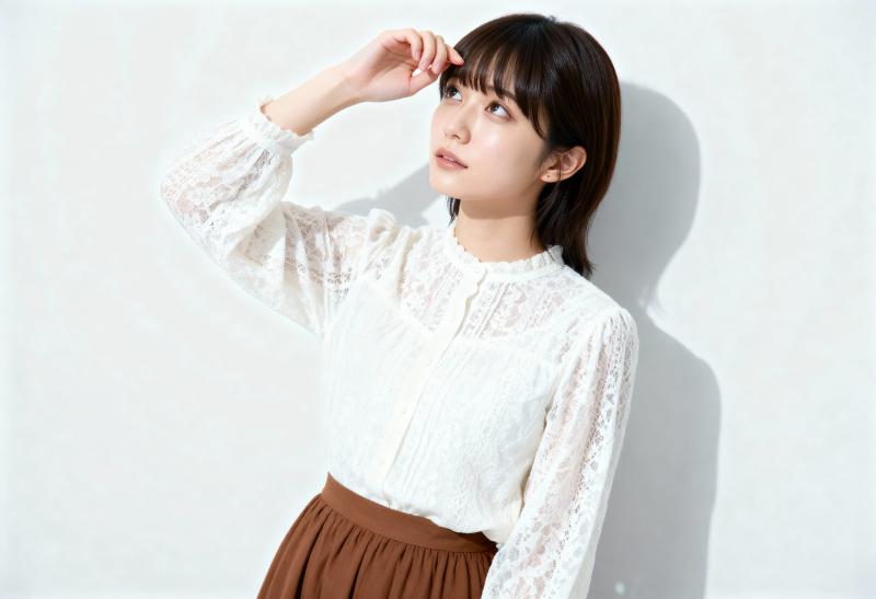 白いレースのブラウスと茶色のスカートを着て、無地の白い壁に向かって自信を持ってポーズ...。