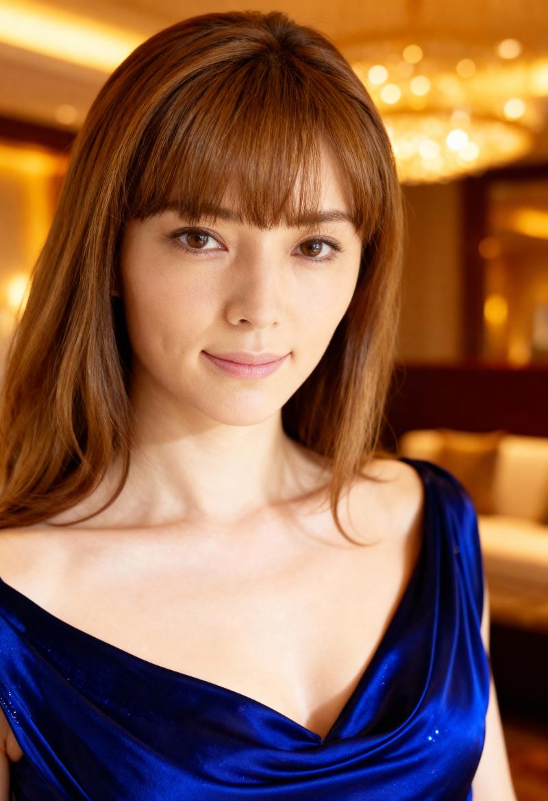 長いストレートの茶色の髪と前髪を持ち、スリムな体を強調する青いワンショルダーのノース...。