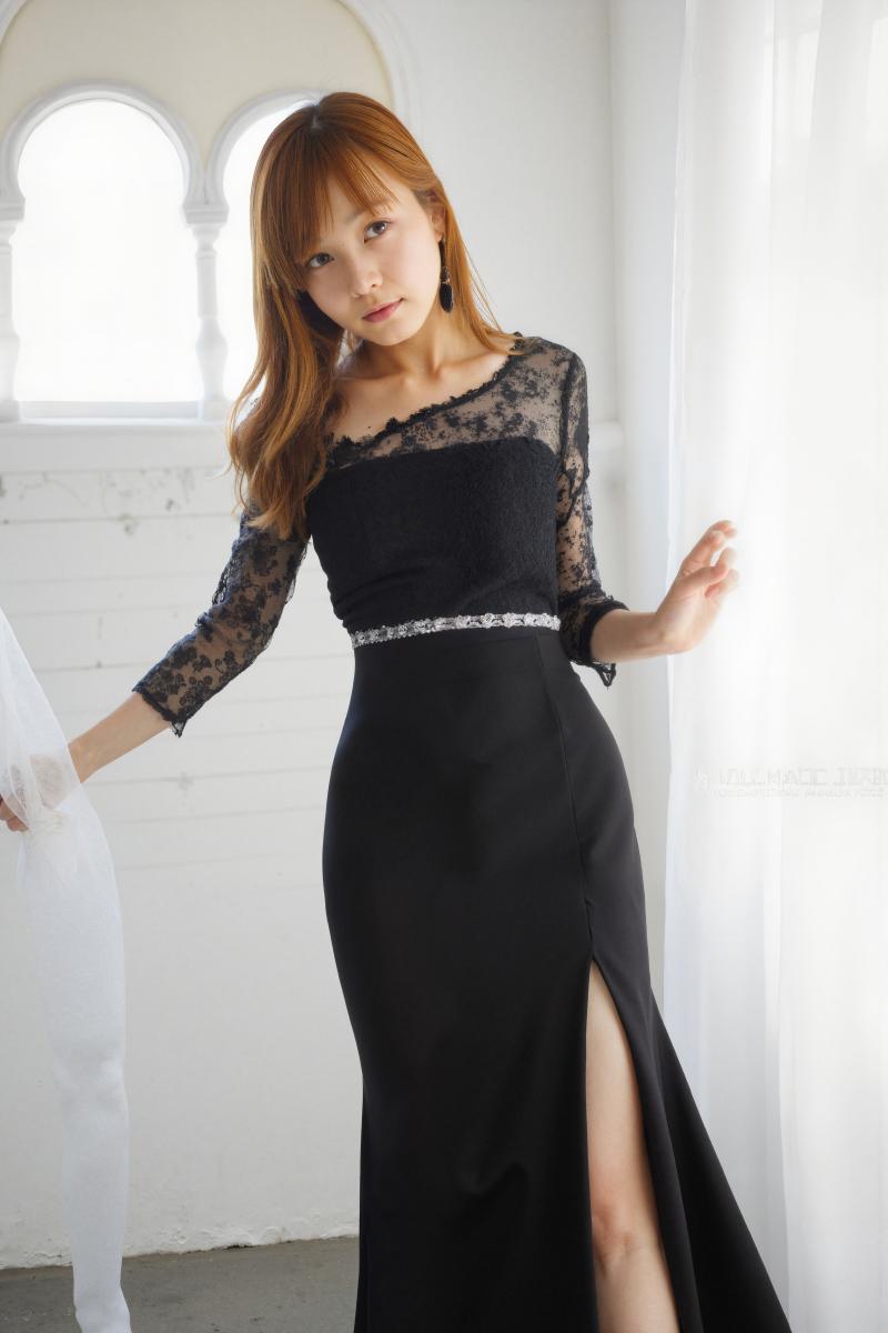 白い壁とアーチ型の窓のある明るい部屋に立つ黒いフォーマルなドレスを着た若い女性を、正...。