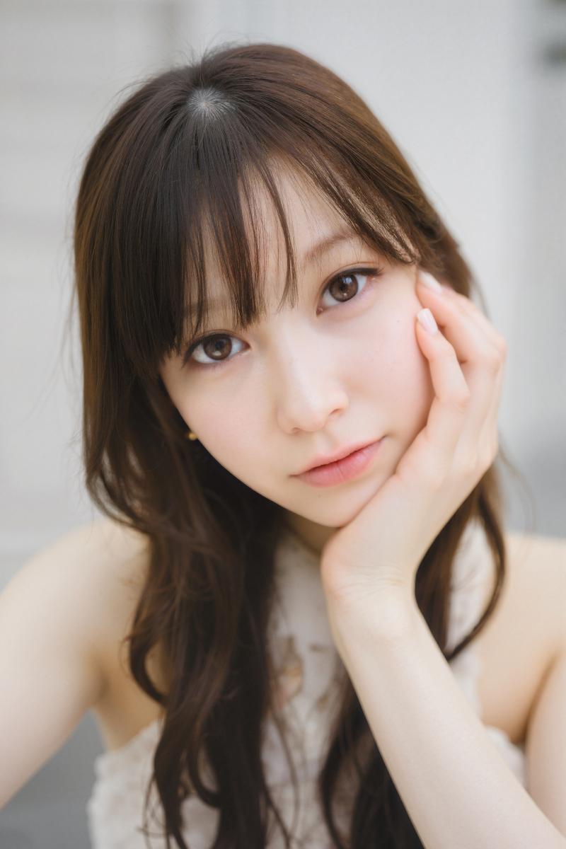 長くウェーブのかかった茶色の髪と白い肌を持つ若いアジア人女性が、あごを手に乗せてポー...。