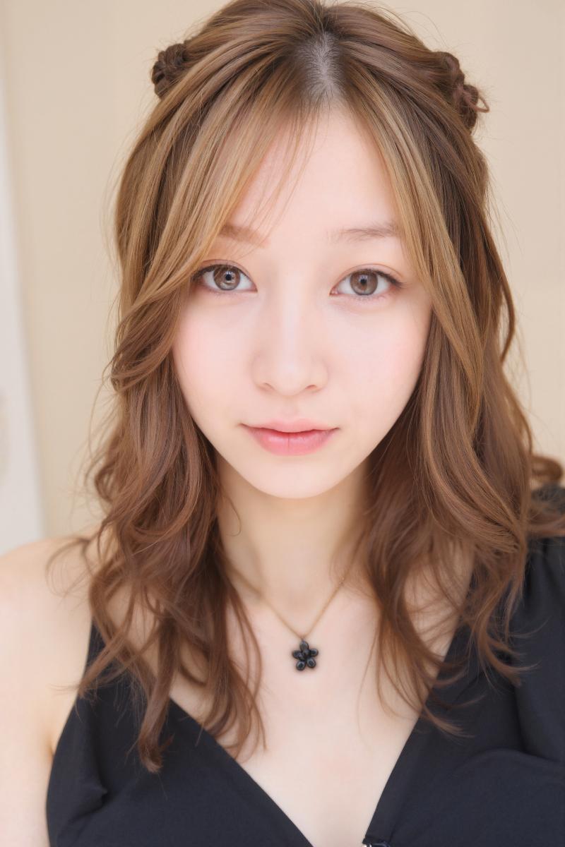 ウェーブのかかった茶色の長い髪を 2 つのお団子にまとめたアジア系の若い女性の接写ポ...。