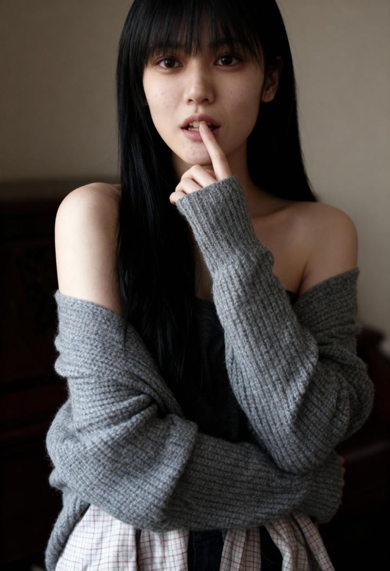 グレーのオフショルダー セーターとチェックのスカートを着て、唇の近くに指を当ててポー...。
