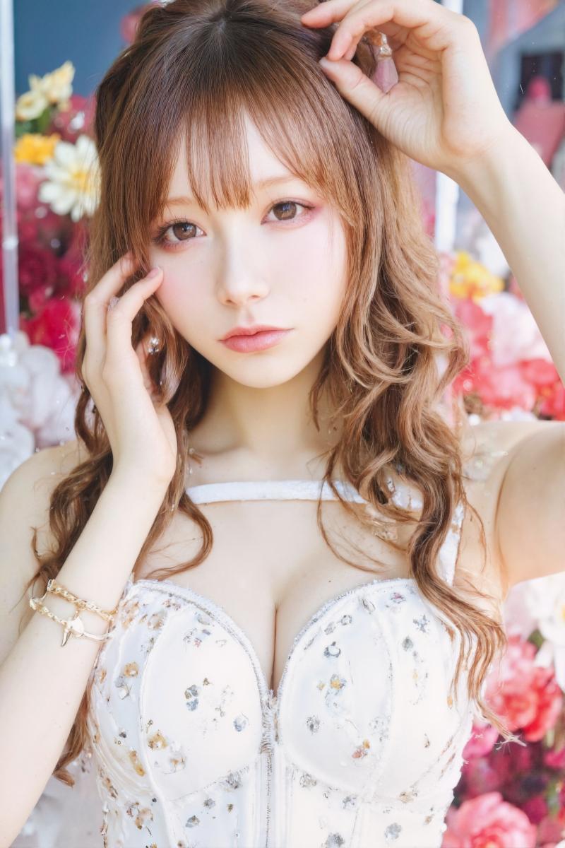 カラフルな花柄の背景の前でポーズをとる若い女性をポートレートアングルから撮影した写実...。