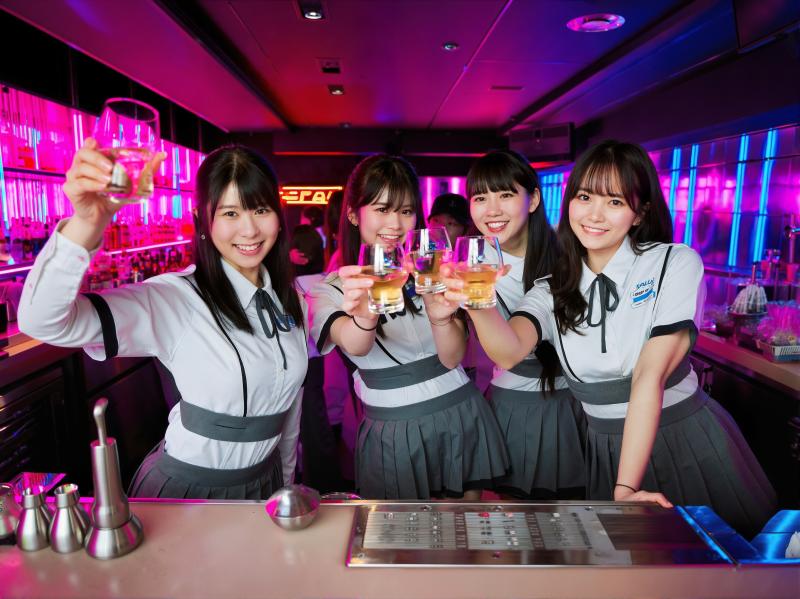 ナイトクラブでドリンクのグラスを持ち、カメラに向かって微笑む 4 人の若いアジア人女...。