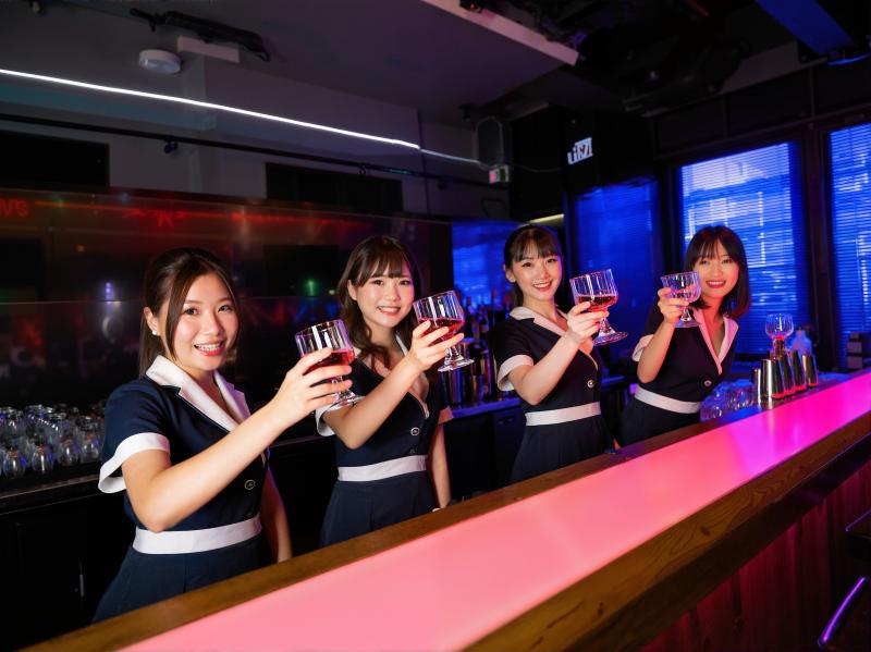 バーカウンターの後ろに立ち、白のアクセントが付いたネイビーブルーの制服を着て赤ワイン...。