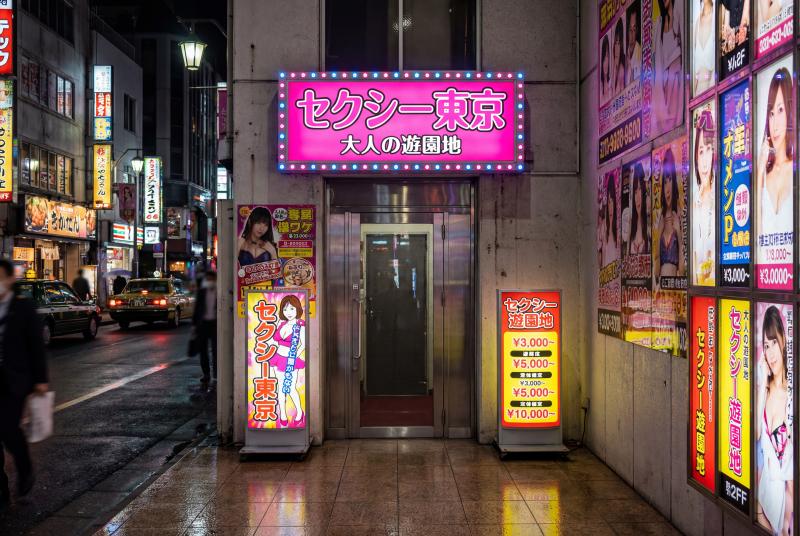 ネオンが輝く夜の日本料理店の入り口をローアングルから撮影した写真。